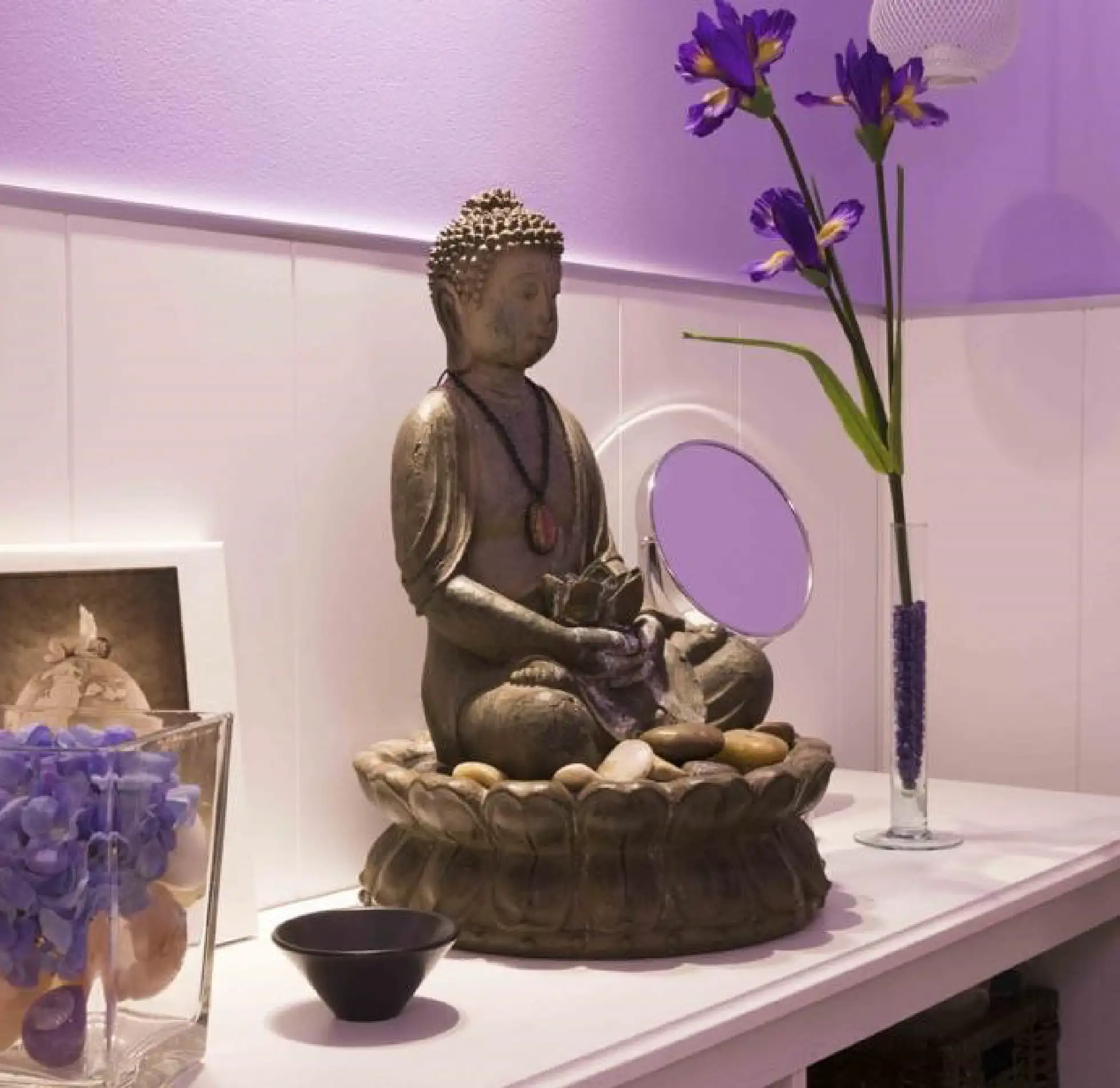 Detalle de la decoración zen del centro de estética con una estatua de Buda, flores y piedras.
