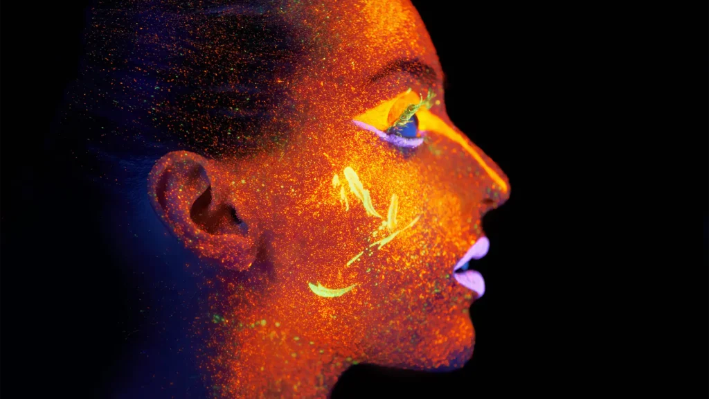 Rostro iluminado con luz ultravioleta que muestra la pigmentación de la piel, usado para ilustrar cómo se detectan y tratan las manchas solares con láser.